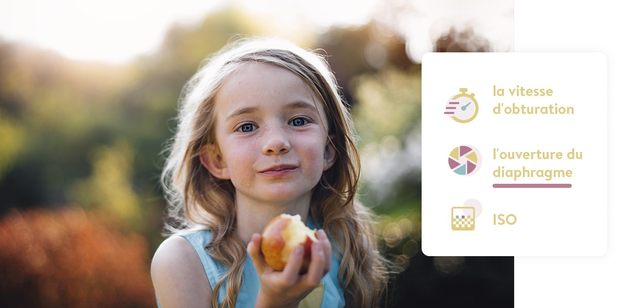 Une petite fille tenant une pomme. Le premier plan est mis au point, l'arrière-plan est flou.