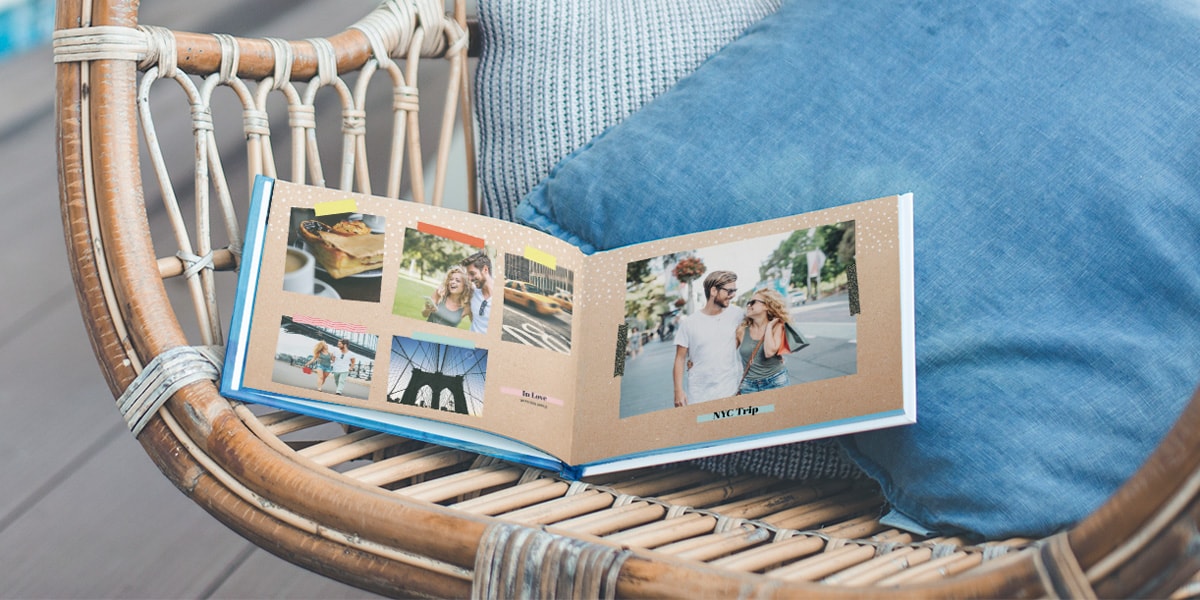 Un livre photo thématique ouvert sur une chaise, avec des photos de vacances à l'intérieur prises par un couple à New York.