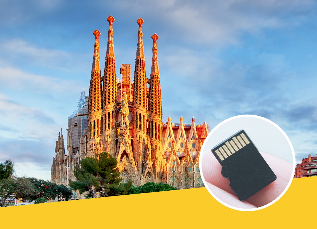 A shot of the Unfinished Cathedral in Barcelona at sunset, with a picture of a standard memory card on a person’s finger within the roundel. 