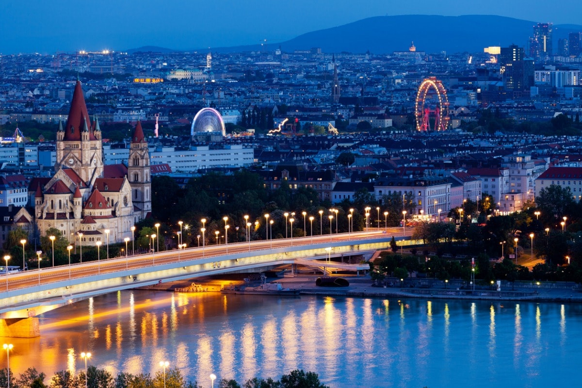 Ein Foto von Wien, aufgenommen am Abend und mit langer Verschlusszeit, damit das Riesenrad im Hintergrund unscharf erscheint. 