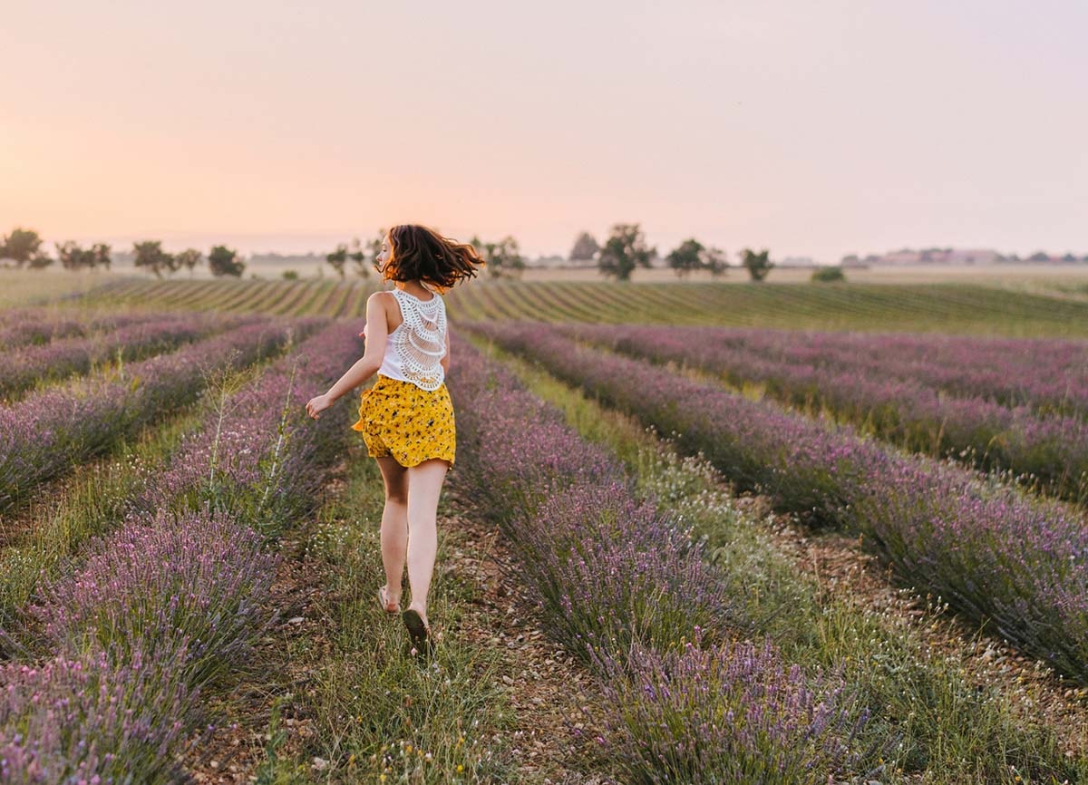 Bild eines Mädchens, das durch ein lilafarbenes Blumenfeld rennt