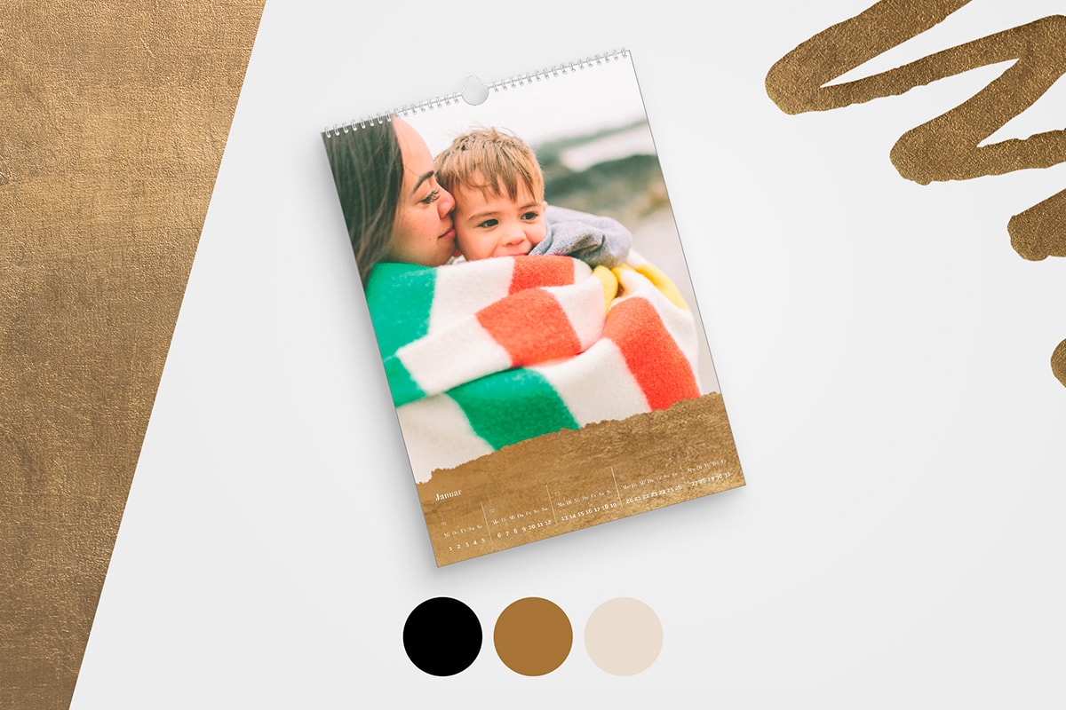 Ein gestalteter Kalender mit einem kleinen Kind, das im Regen spielt, sowie goldenen, schwarzen und Cremefarben. 