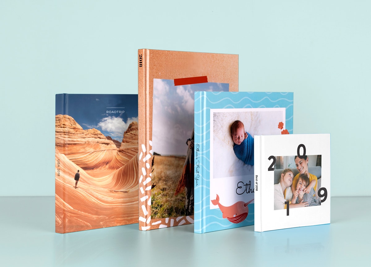 Vier Fotobücher in unterschiedlichen Größen und Formaten, von Babyalben bis zu Reisebüchern.