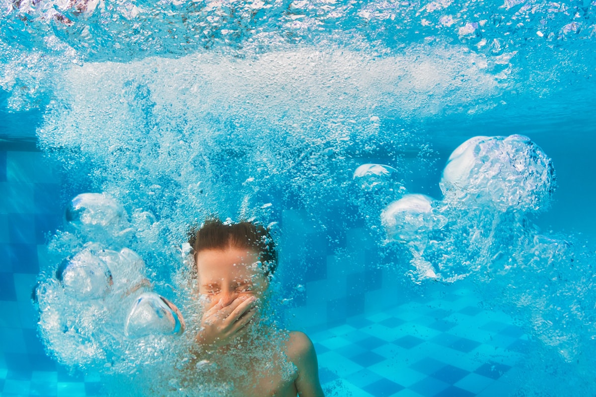 Een onderwaterfoto van een klein kind, nadat hij of zij in het zwembad is gesprongen.