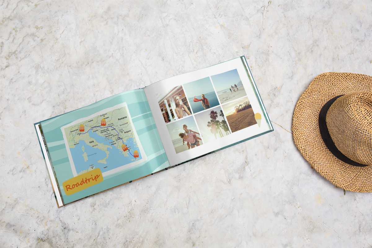 Een opengeslagen reisfotoboek op een marmeren tafelblad. Op de linkerpagina wordt een kaart weergegevens met locaties die zijn uitgezet met clipart van ijslolly's. Op de rechterpagina staat een raster met zes vakantiefoto's.
