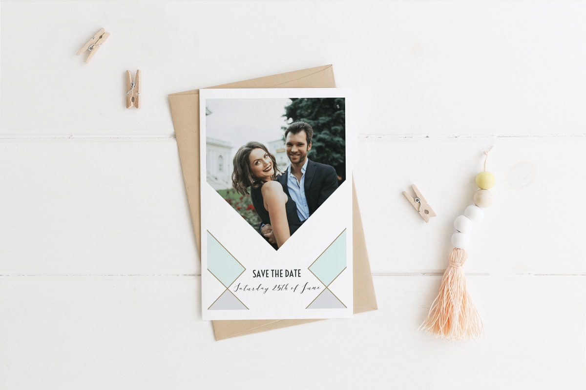 Een persoonlijke save the date fotokaart tegen een witte achtergrond met kleine verspreide houten knijpertjes.