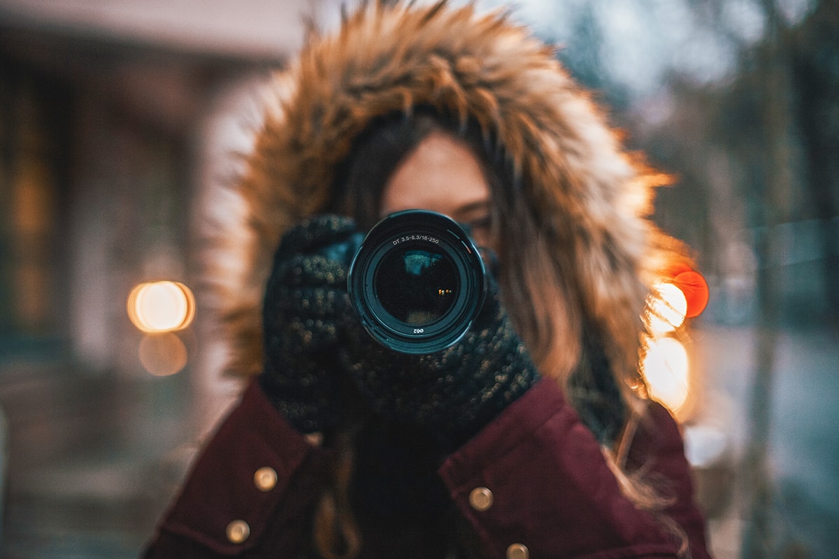 Een foto van een vrouw in een winterjas die een foto neemt met haar spiegelreflexcamera.