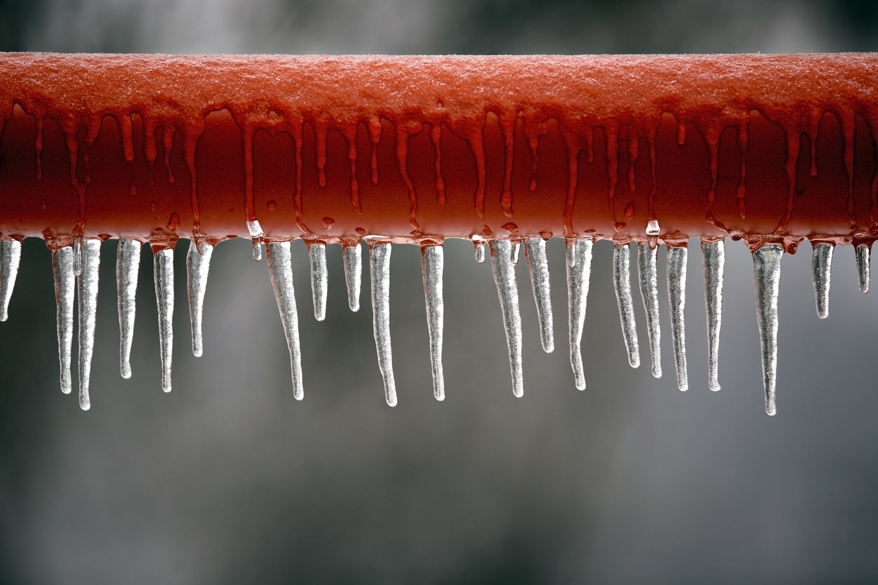 Een rode metalen rail bedekt met ijspegels.