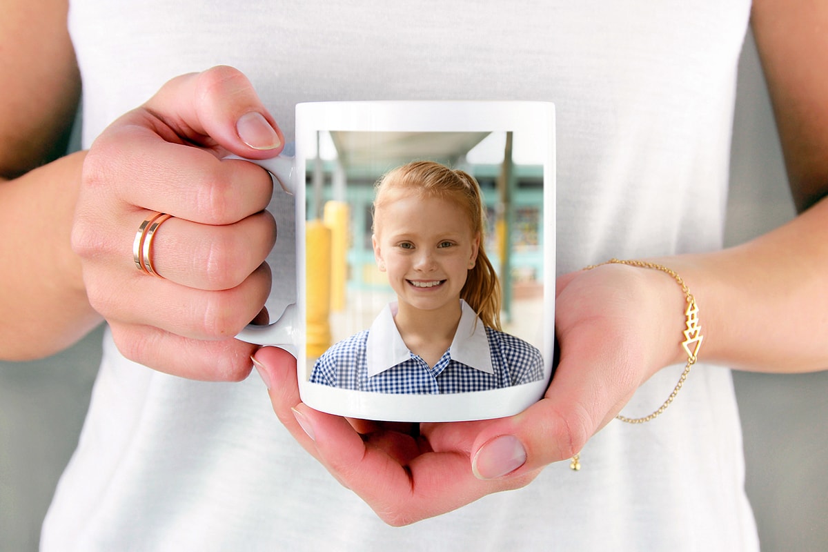 Een vrouw met een mok met daarop een foto van een klein meisje met een zomers jurkje aan, in haar hand. 