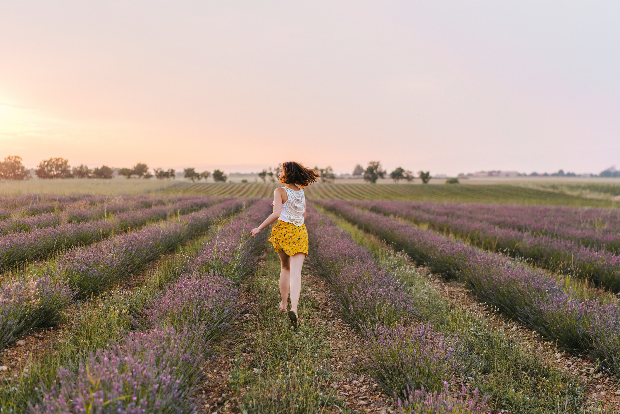 Beeld van een meisje dat door een veld van paarse bloemen rent