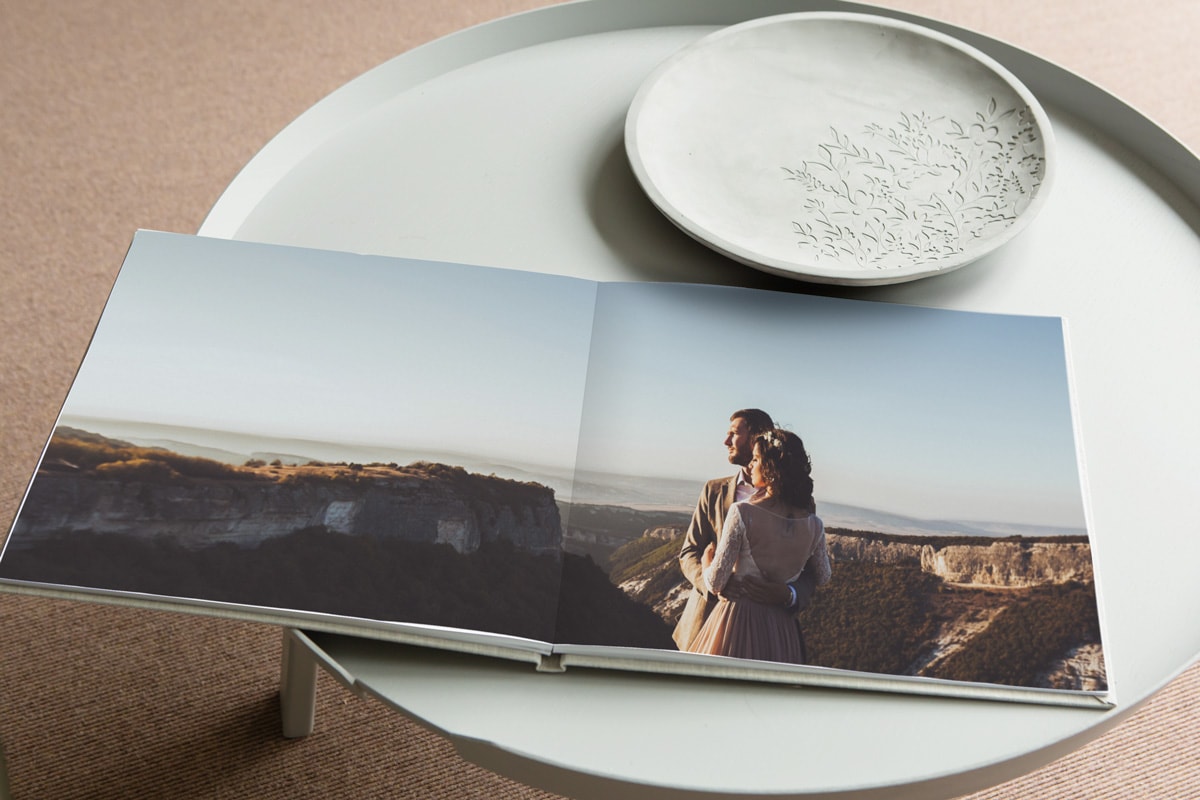 Een open trouwalbum op een koffietafel met één trouwfoto die over twee pagina's wordt weergegeven.
