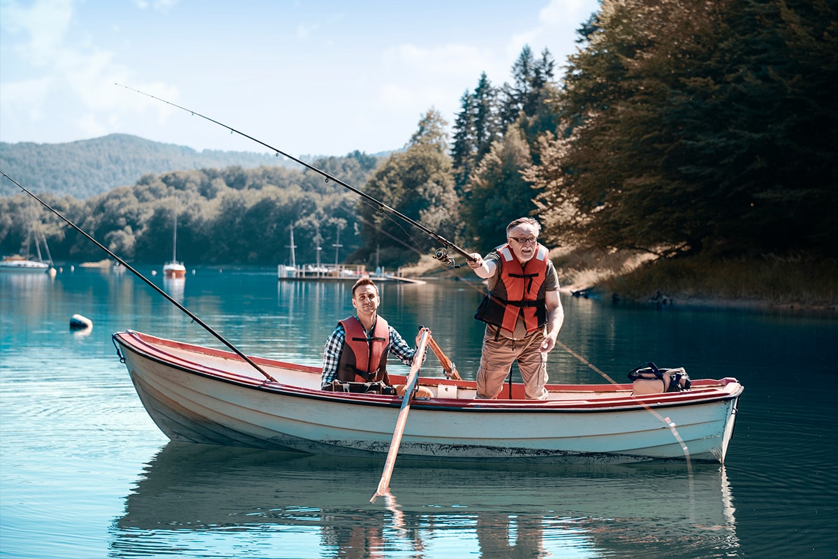Een foto van een oudere man die met zijn zoon in een boot op het meer aan het vissen is.