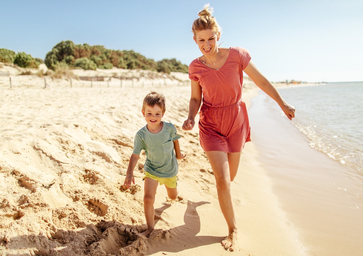 En bild av en kvinna och hennes son springande på stranden.