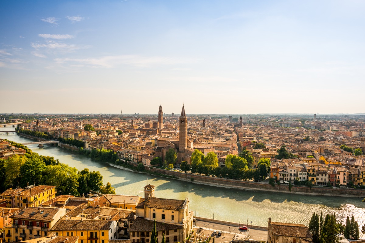 En bild över Veronas takåsar och floden som rinner genom stan, en bild som tagits en klar och solig dag.