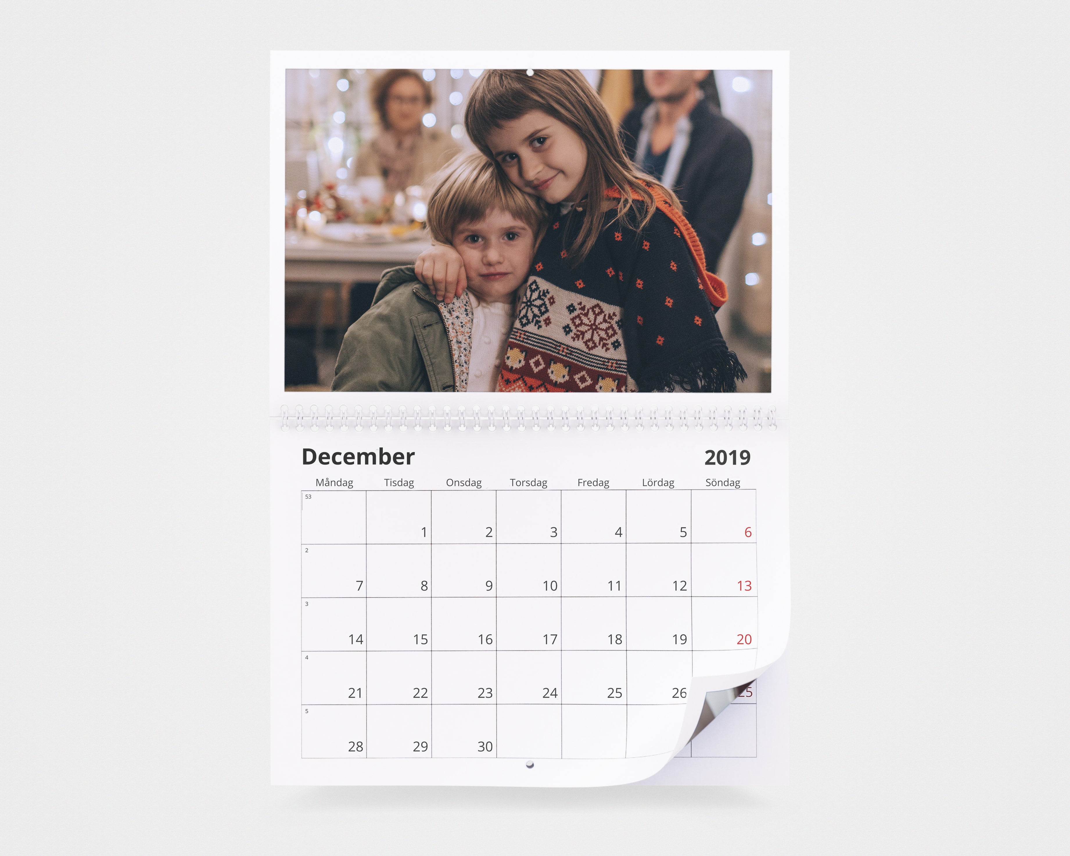 En fotokalender med en bild av två barn med jultröjor och vinterjackor.