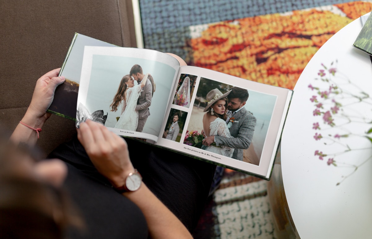 En bild på en sittande kvinna som bläddrar igenom en fördesignad bröllopsfotobok.