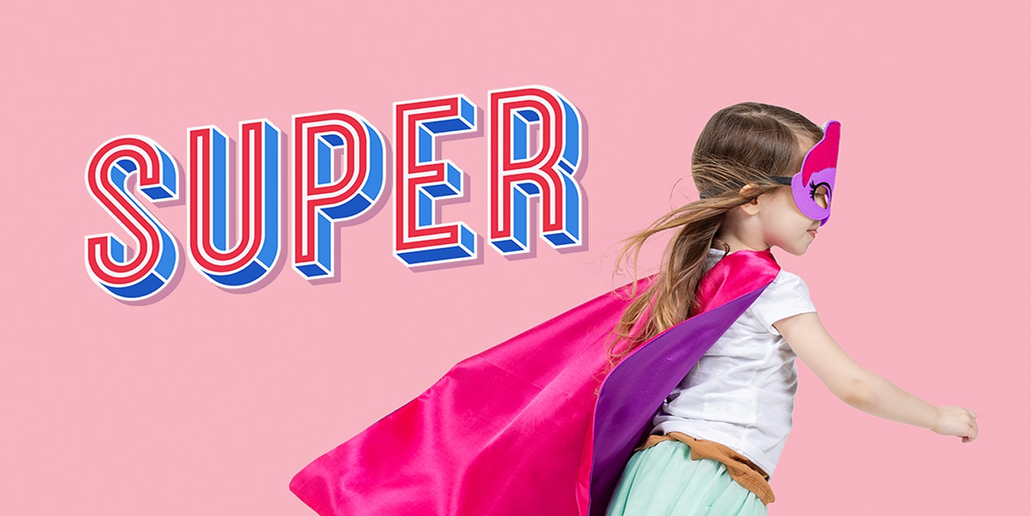 En liten jente på rulleskøyter, kledd som en superhelt i en rosa kappe med ordet ‘super’ i trykkbokstaver på en rosa bakgrunn.