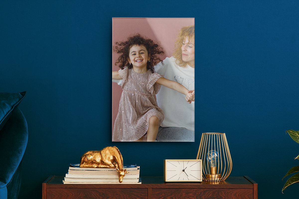Lifestyle shot of an acrylic wall art hanging against a blue wall art. A table with various decorations sit under the wall art.