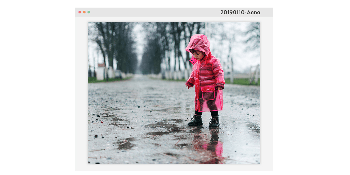 Un homme et une fUne photo d'une petite fille en imperméable rose debout sur un chemin pendant un jour de pluie. L'image est encadrée par une fenêtre d'ordinateur, avec un nom de fichier dans le coin supérieur droit.emme assis avec une petite fille, feuilletant un livre photo de famille.