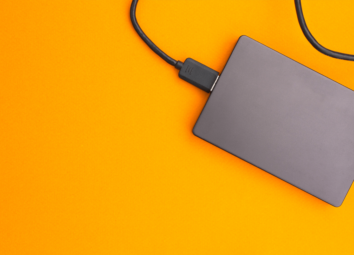 Un cliché plongeant sur un disque dur externe noir sur une surface orange vif.